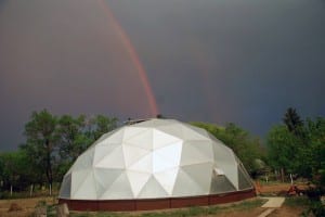 August's Dome of the Month a 42' geodesic greenhouse with a double rainbow in the background
