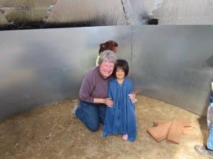 Woman and child posing for a photo inside a Growing Dome above ground pond during construction