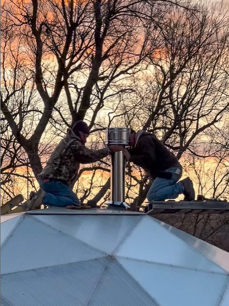 Two Men installing stove pipe on 22' Growing Dome
