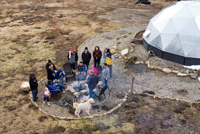 Family gathering outside a backyard greenhouse