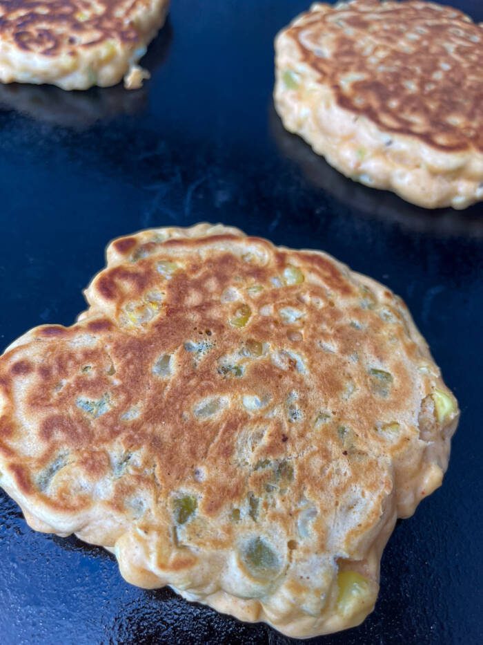 Golden Brown Roasted green chili corn cakes on flat-top grill