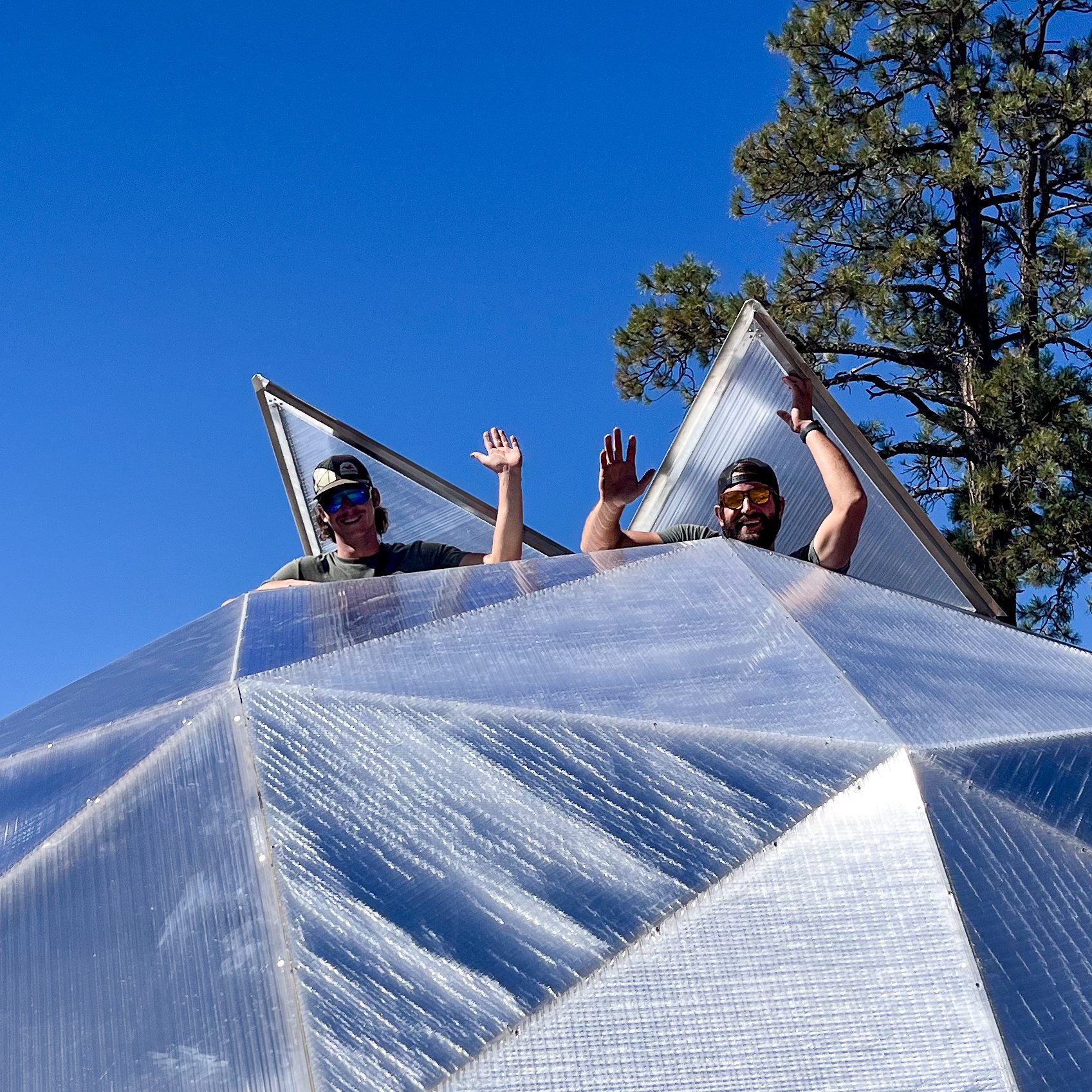 Two greenhouse builders waving