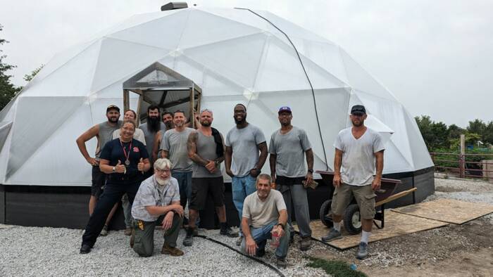 ReEntry program volunteers posing infront of built greenhouse as a team