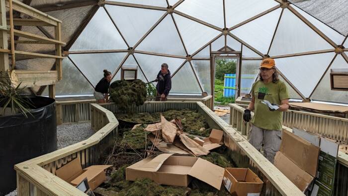 volunteers filling the greenhouses raised beds with soil
