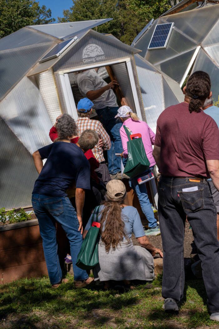 class participants standing outside 15' Growing Dome and watching as the instructor points out maintenance issues