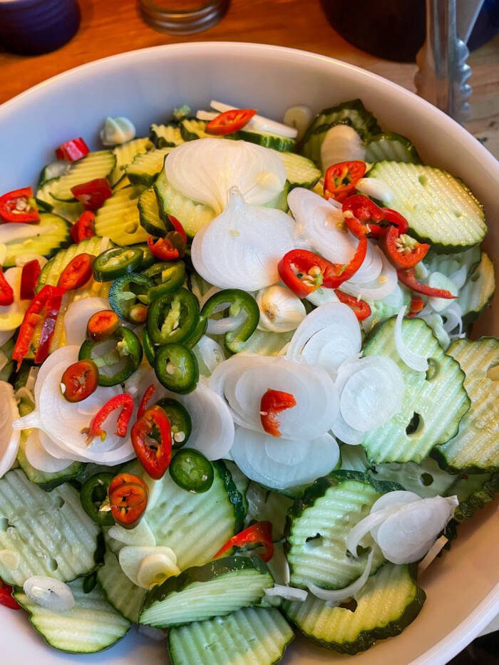 mixing bowl full of sliced cucumbers, onion, and peppers