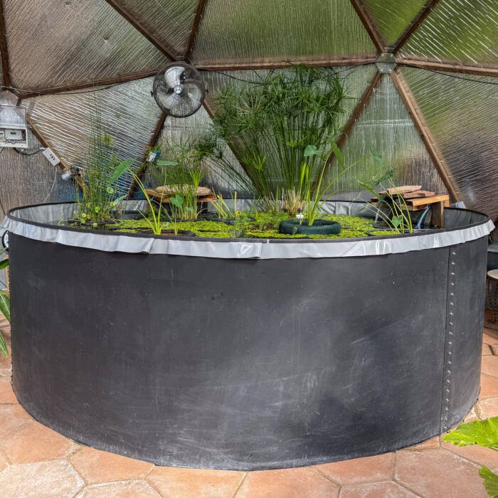 Round sheet metal pond painted mat black with a light grey liner surrounded by a hexagon paver floor