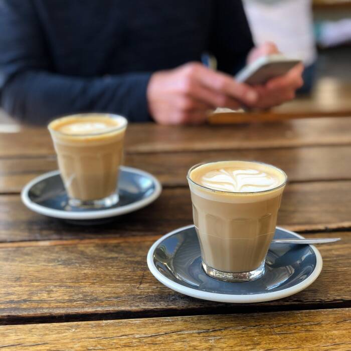 lattes sitting on a table with a person in the background